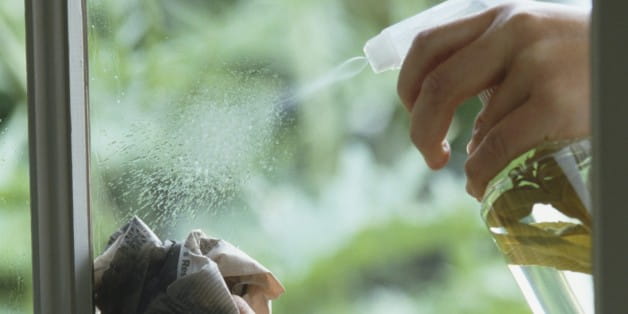 Cleaning window by applying natural solution from spray bottle and rubbing glass with sheet of crumpled newspaper.